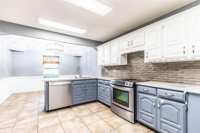 1237 Linkwood Ln, Lancaster, TX 75146 - kitchen with appliances with stainless steel finishes, white cabinetry, a peninsula, light countertops, and tasteful backsplash