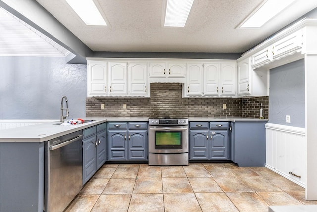 1237 Linkwood Ln, Lancaster, TX 75146 - kitchen with stainless steel appliances, white cabinets, decorative backsplash, light countertops, and a wainscoted wall