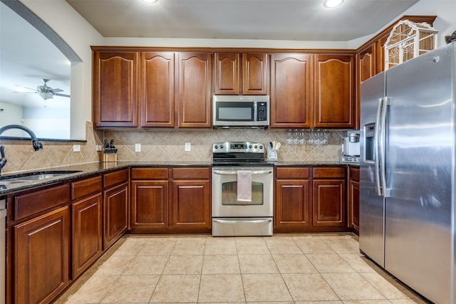 5104 Pebble Beach Trl, Denton, TX 76208 - kitchen featuring stainless steel appliances, dark stone counters, a ceiling fan, decorative backsplash, and recessed lighting