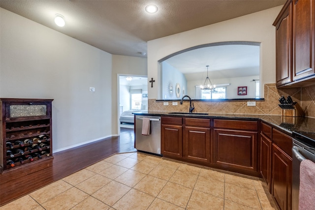 5104 Pebble Beach Trl, Denton, TX 76208 - kitchen with stainless steel dishwasher, backsplash, light tile patterned flooring, stove, and arched walkways