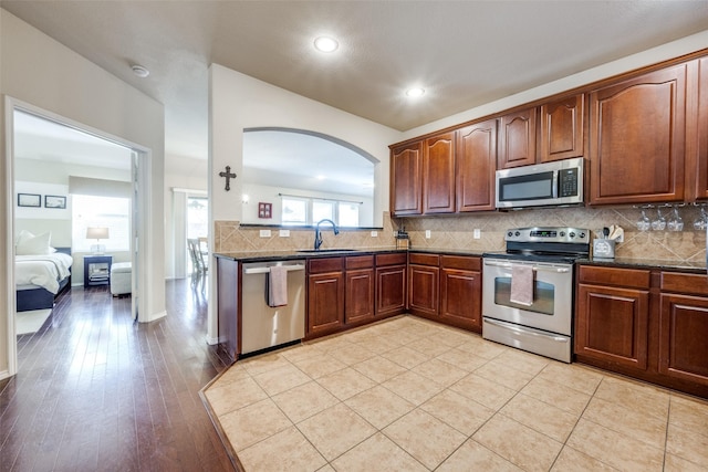 5104 Pebble Beach Trl, Denton, TX 76208 - kitchen with appliances with stainless steel finishes, arched walkways, backsplash, recessed lighting, and light wood finished floors