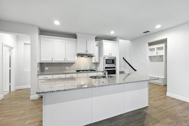 260 Clairmont Dr, Ponder, TX 76259 - kitchen with stainless steel appliances, under cabinet range hood, white cabinets, light wood finished floors, and recessed lighting