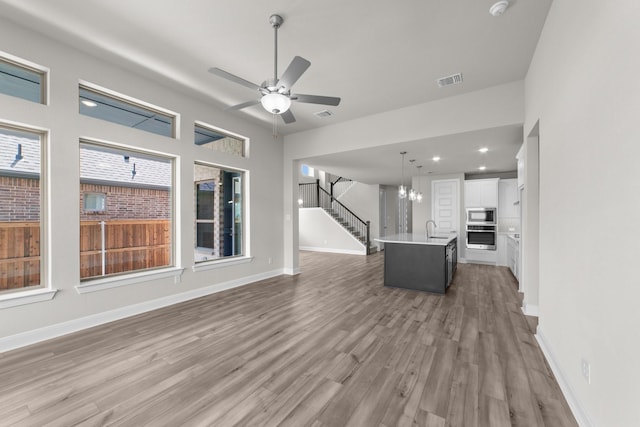 6217 Escarpment Dr, Fort Worth, TX 76112 - unfurnished living room with wood finished floors, a chandelier, ceiling fan, stairway, and recessed lighting