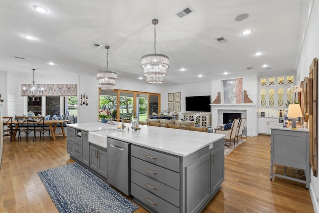 7116 Serrano Dr, Benbrook, TX 76126 - kitchen featuring gray cabinets, a chandelier, stainless steel dishwasher, wood finished floors, and a fireplace