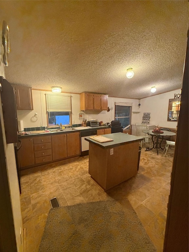 122 Vz County Road 3735, Wills Point, TX 75169 - kitchen with dishwashing machine, a center island, dark countertops, brown cabinets, and a textured ceiling