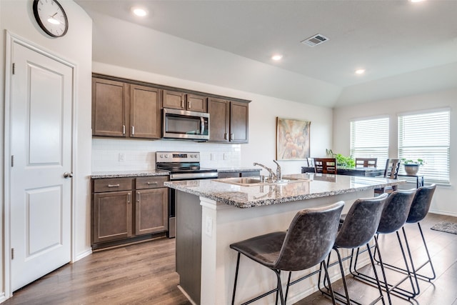 4319 Pyramid Dr, Forney, TX 75126 - kitchen featuring stainless steel appliances, a center island with sink, light stone counters, a breakfast bar, and backsplash