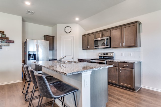 4319 Pyramid Dr, Forney, TX 75126 - kitchen with stainless steel appliances, dark brown cabinetry, light stone counters, backsplash, and light wood-style flooring