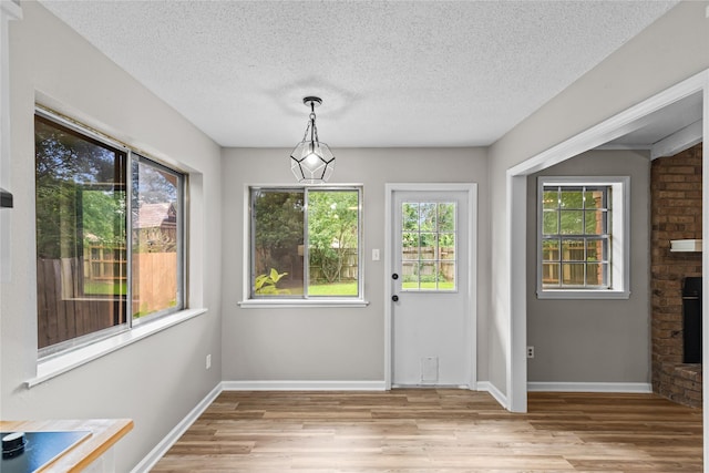 9709 Monticello Dr, Shreveport, LA 71118 - unfurnished dining area with light wood-style floors, healthy amount of natural light, a brick fireplace, and a textured ceiling