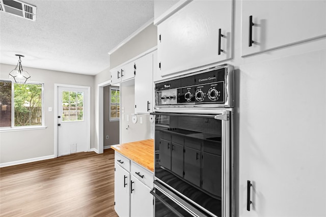 9709 Monticello Dr, Shreveport, LA 71118 - kitchen with wooden counters, white cabinets, wood finished floors, a textured ceiling, and hanging light fixtures