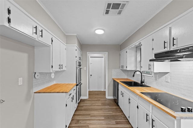 9709 Monticello Dr, Shreveport, LA 71118 - kitchen with black electric cooktop, under cabinet range hood, white cabinetry, decorative backsplash, and light wood-type flooring