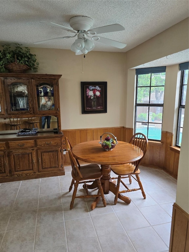 3810 Lucena Ct, Grand Prairie, TX 75052 - dining space featuring a wainscoted wall, a textured ceiling, light tile patterned flooring, wooden walls, and a ceiling fan