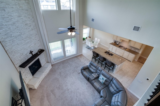 11100 Tanager Ln, Cross Roads, TX 76227 - living room featuring a high ceiling, a stone fireplace, light colored carpet, and ceiling fan
