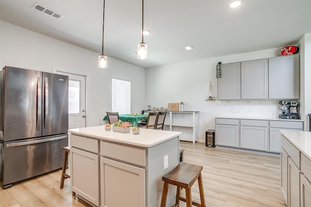 7501 Agarita Ave, Denton, TX 76226 - kitchen featuring freestanding refrigerator, a kitchen bar, light wood-style floors, light countertops, and decorative light fixtures