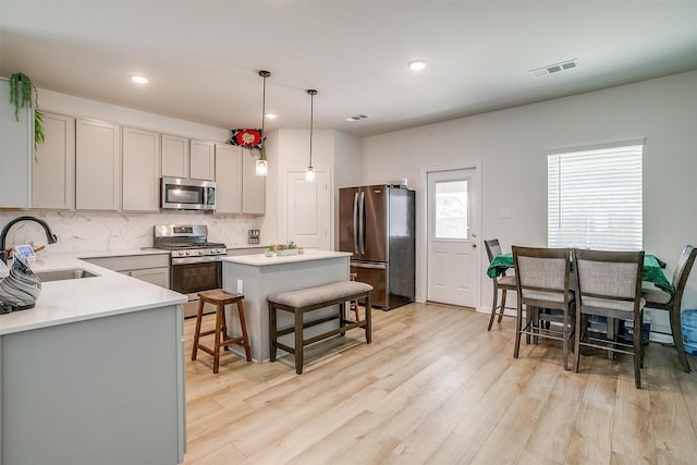7501 Agarita Ave, Denton, TX 76226 - kitchen featuring stainless steel appliances, backsplash, light countertops, light wood-style flooring, and a kitchen island