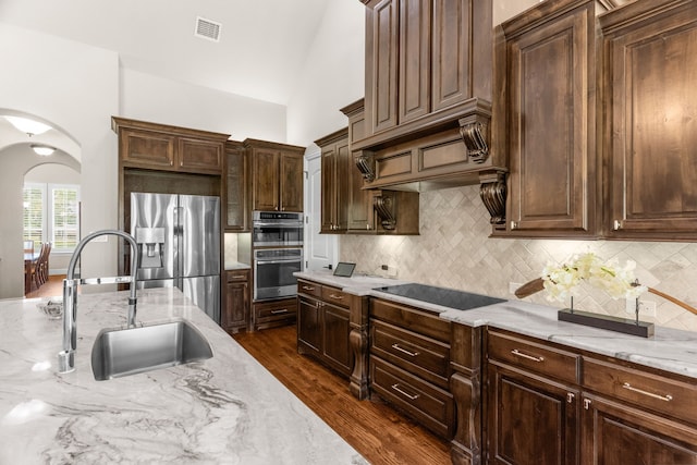 1707 Ponderosa Trl, Sachse, TX 75048 - kitchen featuring appliances with stainless steel finishes, light stone countertops, decorative backsplash, and dark wood finished floors