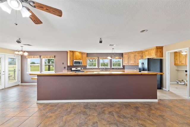 875 Cr221, Stephenville, TX 76401 - kitchen with stainless steel microwave, stove, decorative light fixtures, a textured ceiling, and a chandelier