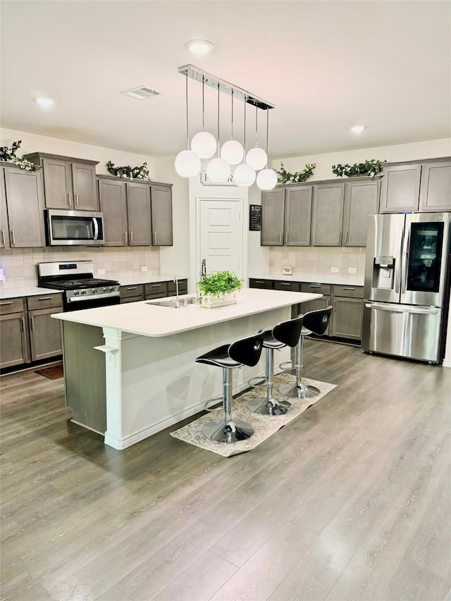 3316 Azure Ln, Celina, TX 75009 - kitchen featuring appliances with stainless steel finishes, decorative backsplash, wood finished floors, a kitchen bar, and recessed lighting