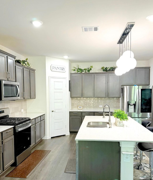 3316 Azure Ln, Celina, TX 75009 - kitchen with appliances with stainless steel finishes, backsplash, wood finished floors, a kitchen bar, and an island with sink