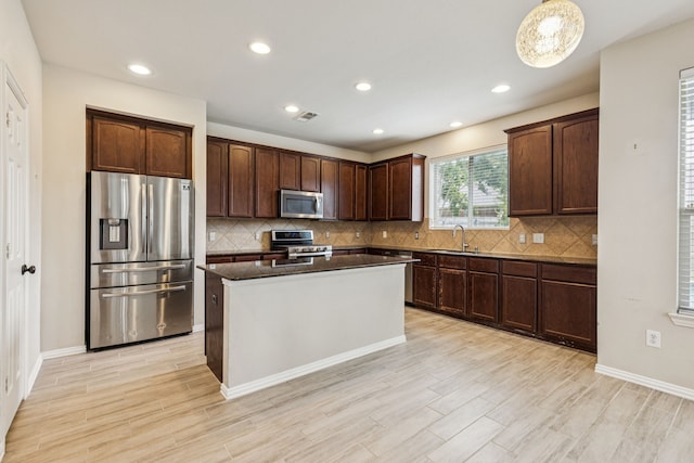 326 Blackhaw Dr, Fate, TX 75087 - kitchen featuring appliances with stainless steel finishes, decorative backsplash, a center island, light wood-style floors, and recessed lighting