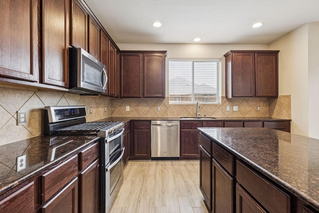 326 Blackhaw Dr, Fate, TX 75087 - kitchen with appliances with stainless steel finishes, dark stone countertops, recessed lighting, dark brown cabinetry, and backsplash
