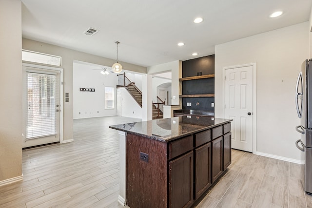 326 Blackhaw Dr, Fate, TX 75087 - kitchen with freestanding refrigerator, a ceiling fan, dark brown cabinetry, light wood-style floors, and dark stone counters