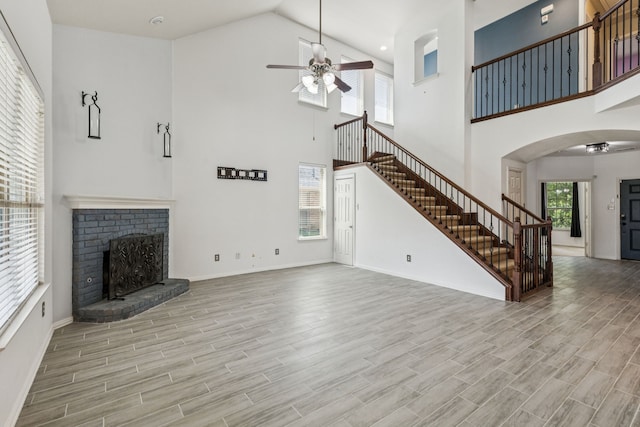 326 Blackhaw Dr, Fate, TX 75087 - unfurnished living room with a ceiling fan, stairs, high vaulted ceiling, a brick fireplace, and wood finished floors