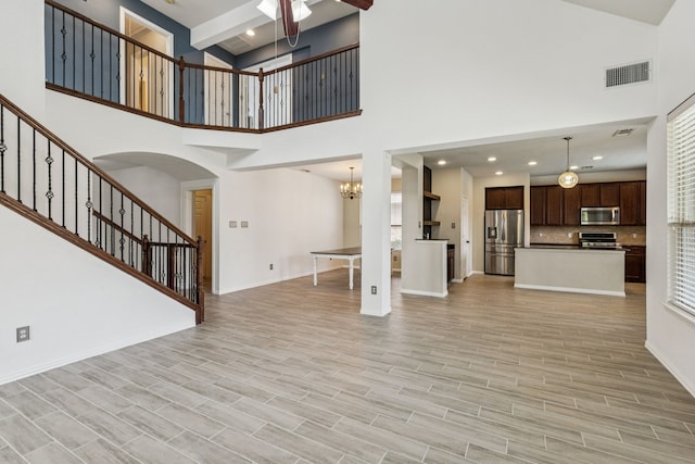 326 Blackhaw Dr, Fate, TX 75087 - unfurnished living room featuring stairway, a towering ceiling, a ceiling fan, arched walkways, and a chandelier