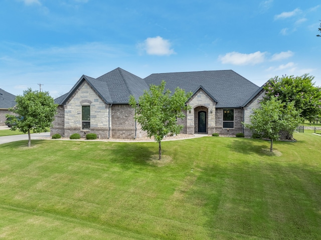 10107 Ravenswood Rd, Granbury, TX 76049 - french country style house with stone siding, a front lawn, and roof with shingles