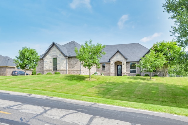 10107 Ravenswood Rd, Granbury, TX 76049 - french country inspired facade with a front yard, stone siding, brick siding, and a shingled roof