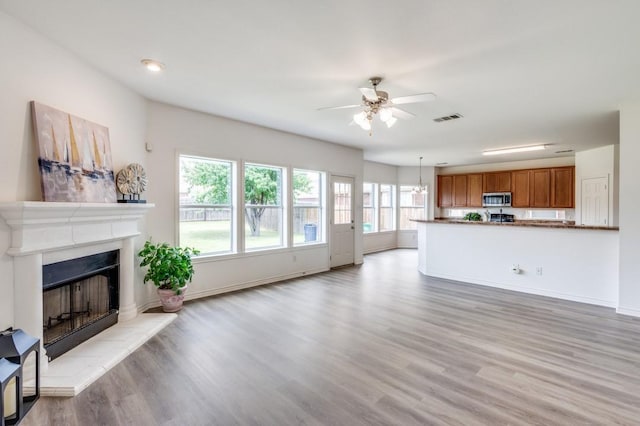 2601 Pinto Dr, Denton, TX 76210 - unfurnished living room with a fireplace with raised hearth, a ceiling fan, and light wood-style floors