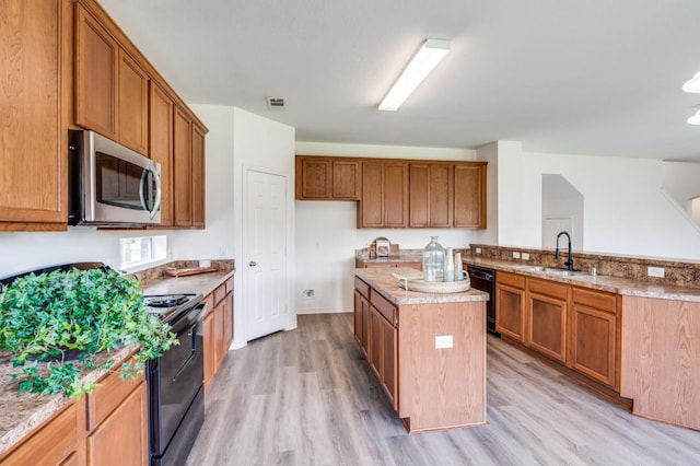 2601 Pinto Dr, Denton, TX 76210 - kitchen with black appliances, light wood finished floors, a kitchen island, brown cabinets, and a peninsula