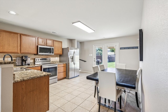 2124 Franks St, Fort Worth, TX 76177 - kitchen with appliances with stainless steel finishes, tasteful backsplash, stone countertops, light tile patterned floors, and french doors