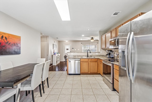 2124 Franks St, Fort Worth, TX 76177 - kitchen featuring appliances with stainless steel finishes, a peninsula, light tile patterned flooring, light stone countertops, and recessed lighting