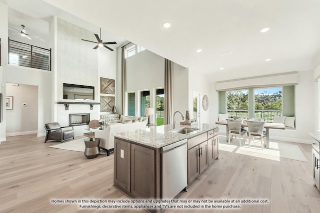 2301 Christopher Rd, Mansfield, TX 76063 - kitchen featuring dishwasher, light wood-style floors, ceiling fan, light stone countertops, and a kitchen island with sink