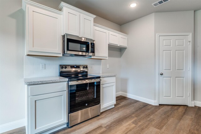 2726 Lawrence St, Dallas, TX 75215 - kitchen featuring stainless steel appliances, light wood finished floors, decorative backsplash, white cabinets, and recessed lighting