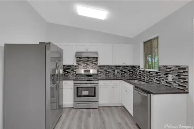 635 Browning St, Shreveport, LA 71106 - kitchen with stainless steel appliances, dark countertops, lofted ceiling, white cabinets, and light wood finished floors