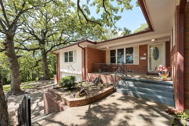 1719 W Day St, Denison, TX 75020 - doorway to property featuring brick siding, covered porch, and a garage