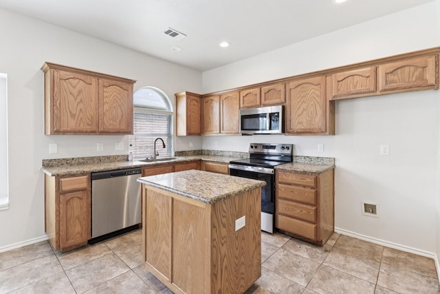 5901 Ozark Dr, Fort Worth, TX 76131 - kitchen with stainless steel appliances, a center island, light stone counters, brown cabinets, and recessed lighting