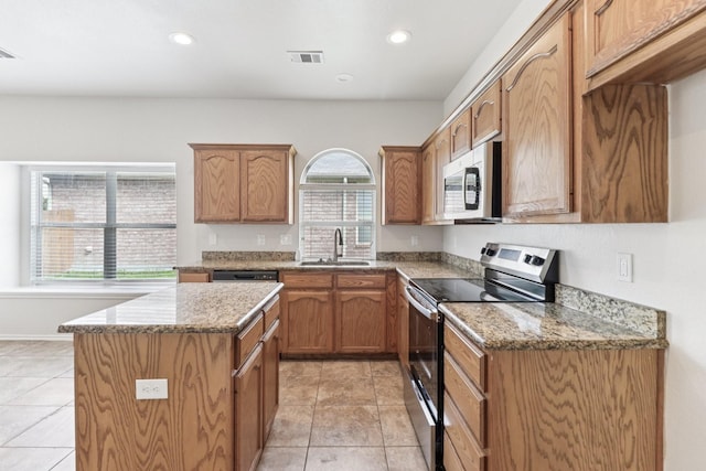 5901 Ozark Dr, Fort Worth, TX 76131 - kitchen featuring appliances with stainless steel finishes, a kitchen island, light stone countertops, light tile patterned floors, and recessed lighting