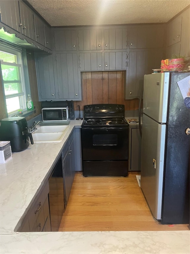 2810 N Mountain View Rd, Granbury, TX 76048 - kitchen with black appliances, light wood-style floors, a textured ceiling, and gray cabinetry