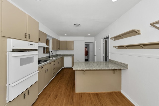 6225 Franwood Ter, Fort Worth, TX 76112 - kitchen featuring white appliances, a warming drawer, a peninsula, wood finished floors, and tasteful backsplash