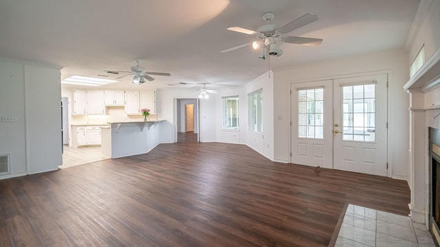 111 Scenic Dr, Dublin, TX 76446 - unfurnished living room featuring a ceiling fan, wood finished floors, a fireplace with flush hearth, crown molding, and french doors