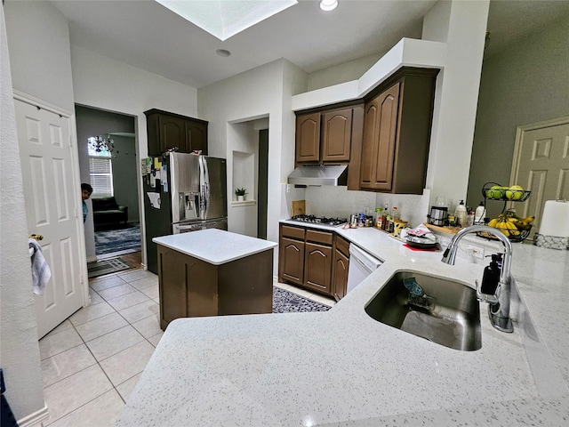1412 Meadow Dr, Irving, TX 75063 - kitchen featuring exhaust hood, a skylight, appliances with stainless steel finishes, light countertops, and dark brown cabinetry