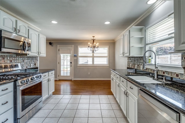 6314 Woodcrest Ln, Dallas, TX 75214 - kitchen featuring appliances with stainless steel finishes, light tile patterned floors, a chandelier, white cabinetry, and crown molding