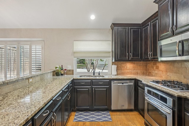 5229 Brettenmeadow Dr, Grapevine, TX 76051 - kitchen featuring appliances with stainless steel finishes, light wood-style flooring, light stone countertops, and backsplash