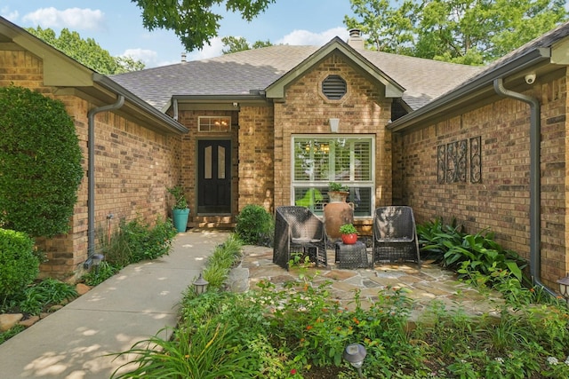 5229 Brettenmeadow Dr, Grapevine, TX 76051 - property entrance with a shingled roof, brick siding, a chimney, and a surveillance system