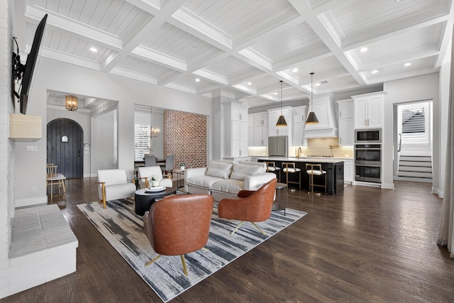 3387 Bellcrest Way, Celina, TX 75009 - living area with arched walkways, stairway, beam ceiling, coffered ceiling, and dark wood finished floors