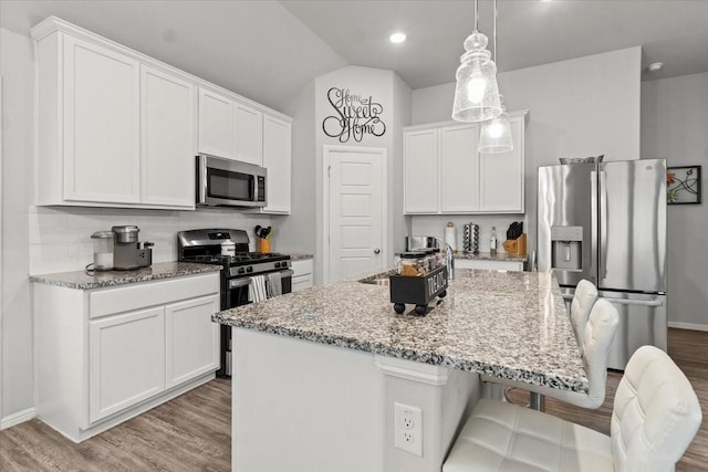 7118 Pampas Pl, Grand Prairie, TX 76804 - kitchen featuring appliances with stainless steel finishes, wood finished floors, white cabinets, light stone countertops, and lofted ceiling