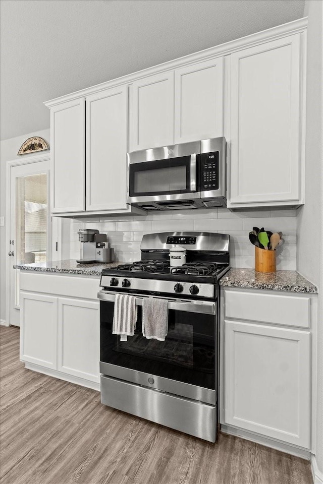 7118 Pampas Pl, Grand Prairie, TX 76804 - kitchen featuring stainless steel appliances, decorative backsplash, light wood-style floors, and light stone counters