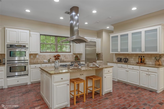 1078 Waters Edge Cir, Shreveport, LA 71106 - kitchen featuring stainless steel appliances, ornamental molding, island exhaust hood, brick flooring, and decorative backsplash
